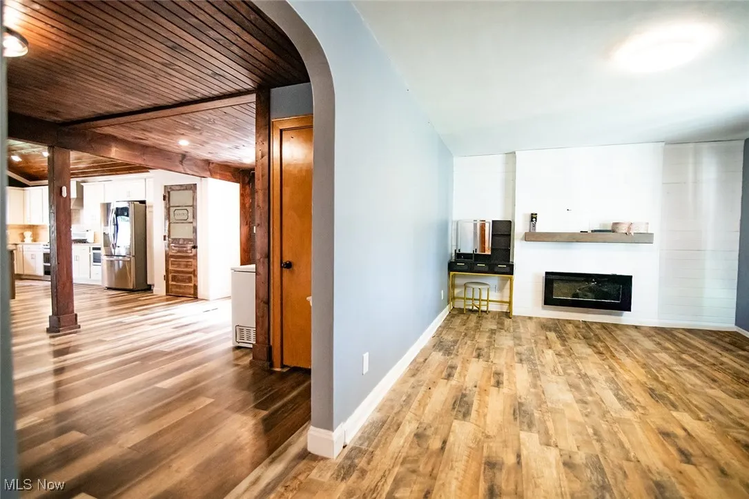 Unfurnished living room featuring arched walkways, light wood finished floors, and a fireplace
