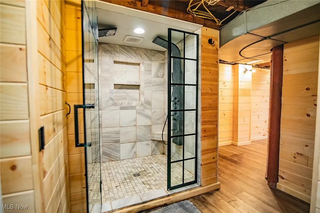 Full bathroom featuring a walk in shower, wood finished floors, recessed lighting, and wooden walls