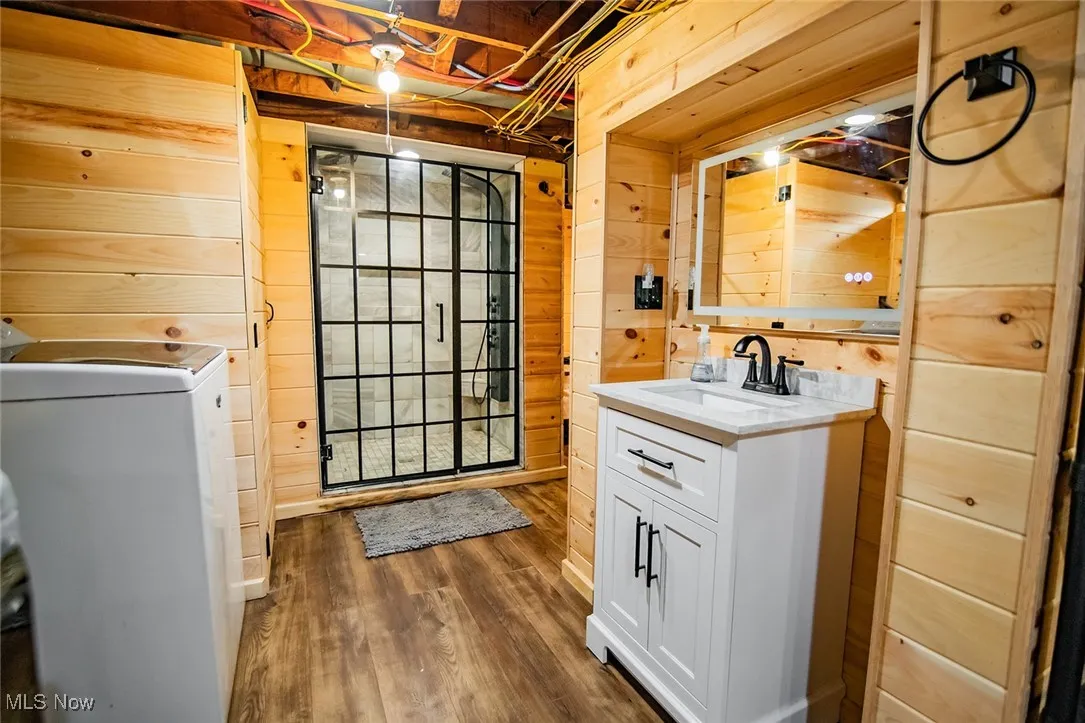 Laundry area with wooden walls, washer / clothes dryer, and dark wood-style floors