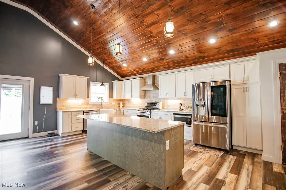 Kitchen featuring stainless steel appliances, tasteful backsplash, light stone countertops, wood ceiling, and pendant lighting