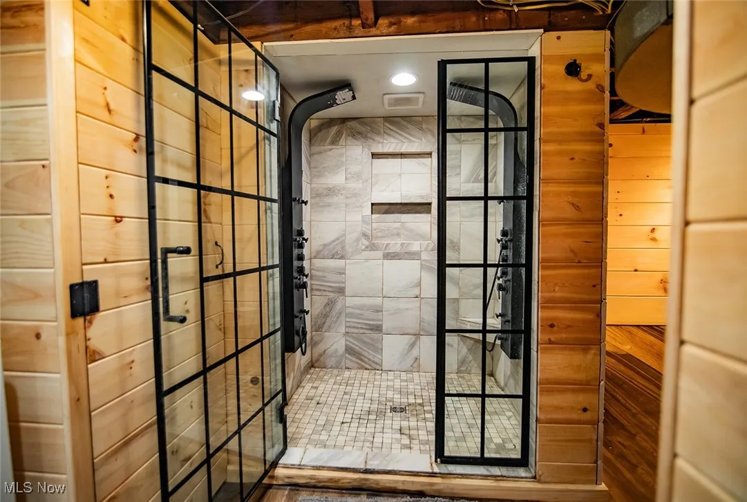 Full bathroom with walk in shower and wood walls