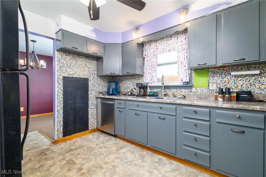 Kitchen with freestanding refrigerator, ceiling fan, tasteful backsplash, stainless steel dishwasher, and a chandelier