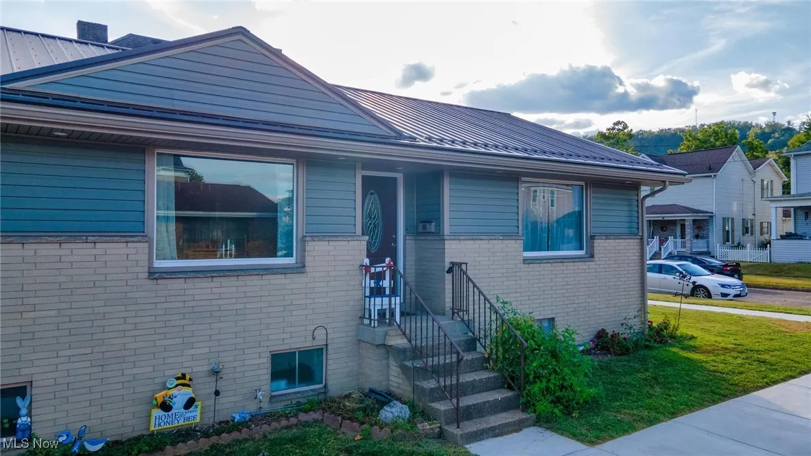 Bungalow-style house featuring a metal roof, brick siding, a front lawn, and a standing seam roof