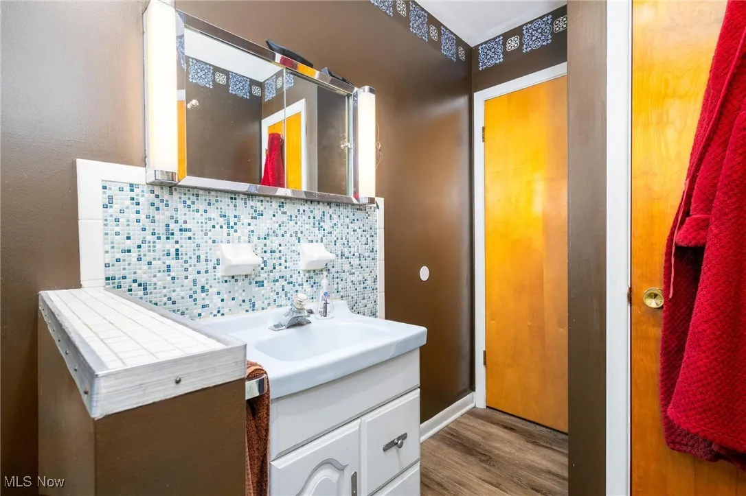 Bathroom with vanity, backsplash, and wood finished floors