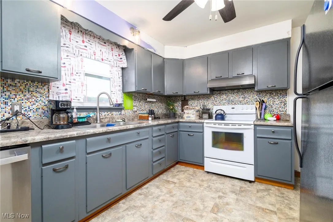 Kitchen featuring tasteful backsplash, white range with electric stovetop, freestanding refrigerator, and stainless steel dishwasher