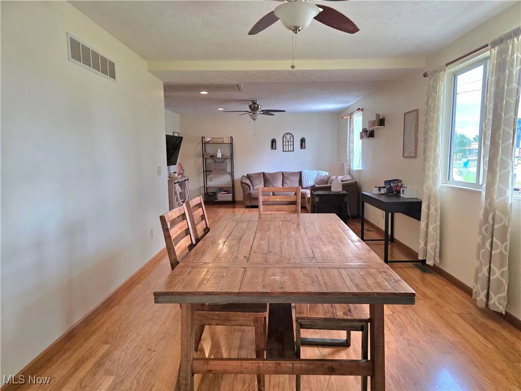 Dining room featuring a textured ceiling, light wood-type flooring, and a ceiling fan