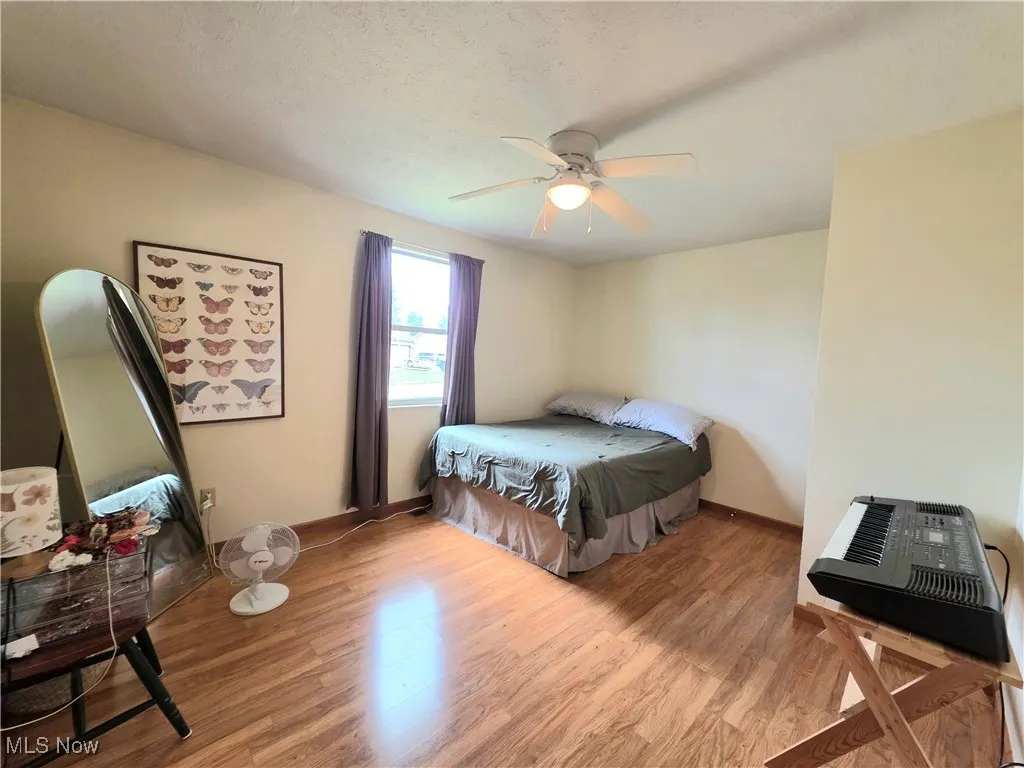 Bedroom with light wood-type flooring, a textured ceiling, and ceiling fan