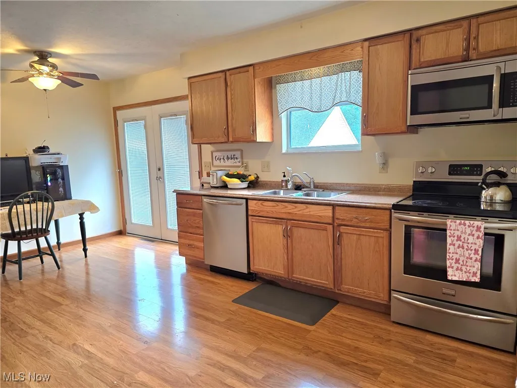 Kitchen with appliances with stainless steel finishes, french doors, light wood-style floors, and brown cabinets