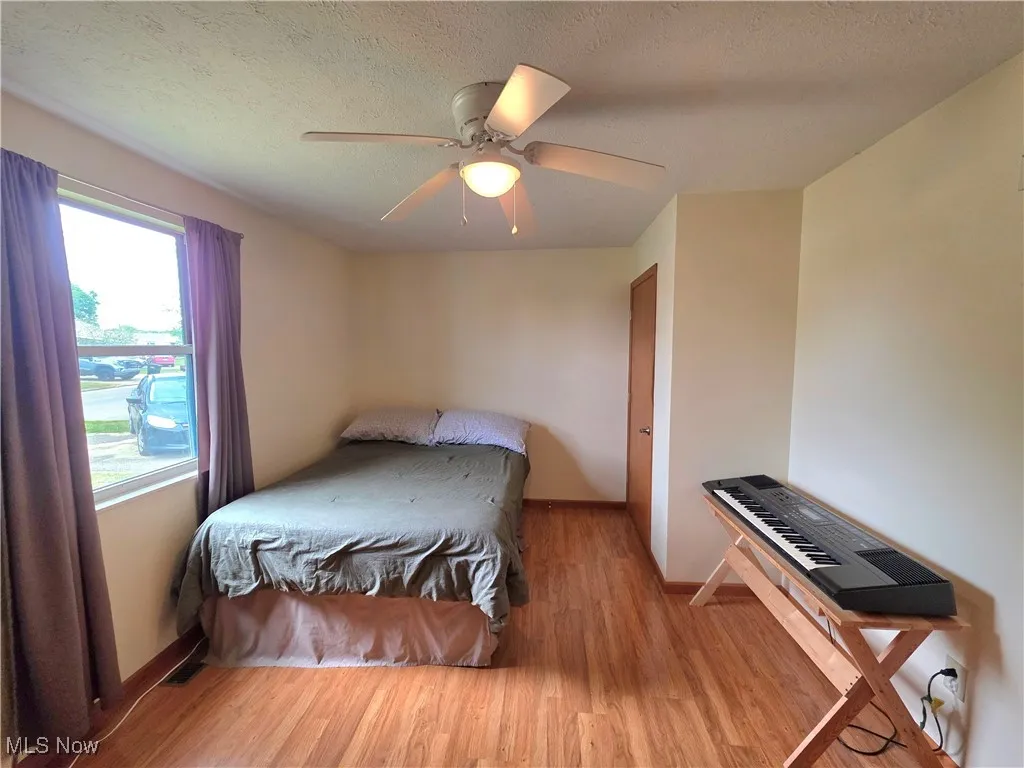 Bedroom with light wood finished floors, a textured ceiling, and ceiling fan