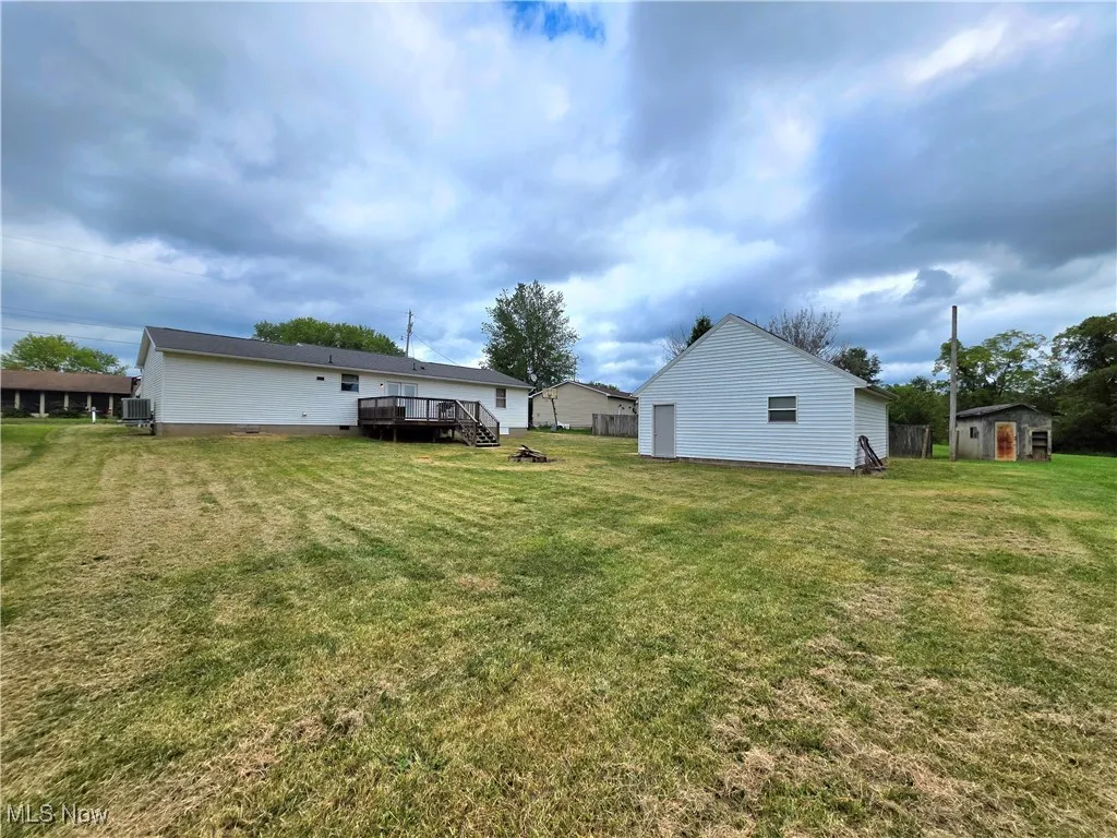 View of grassy yard featuring a deck and a storage shed