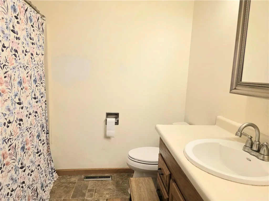 Full bath with vanity, a shower stall, and dark stone finish flooring