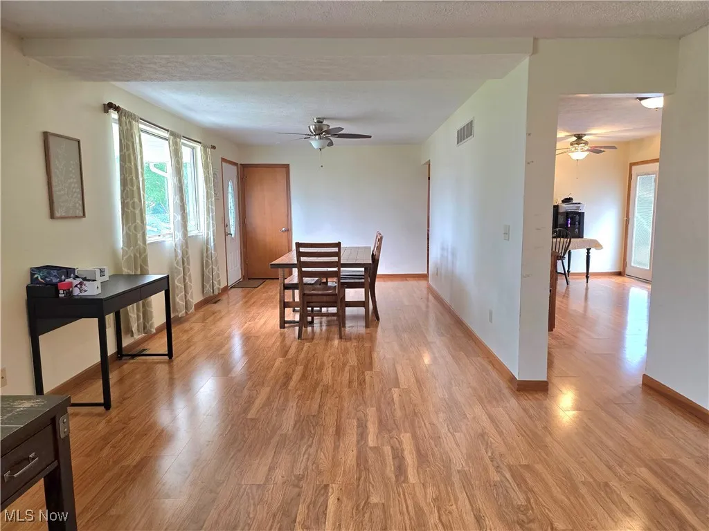 Dining space featuring light wood-type flooring, ceiling fan, and a textured ceiling