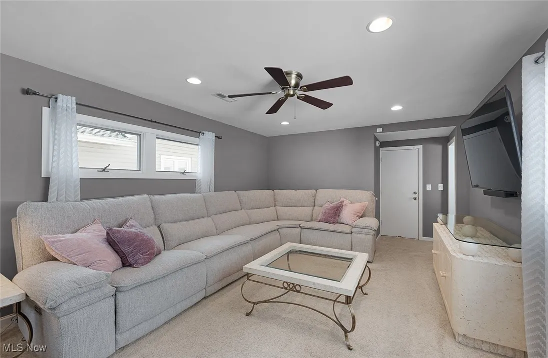 Carpeted living room featuring ceiling fan and recessed lighting