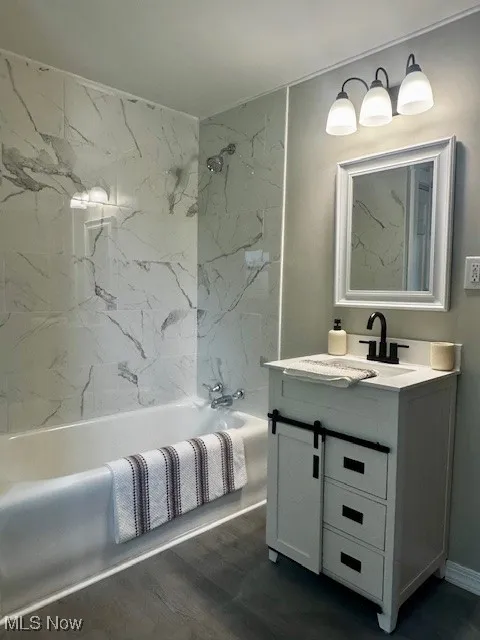 Full bath featuring vanity, shower / bath combination, and wood finished floors