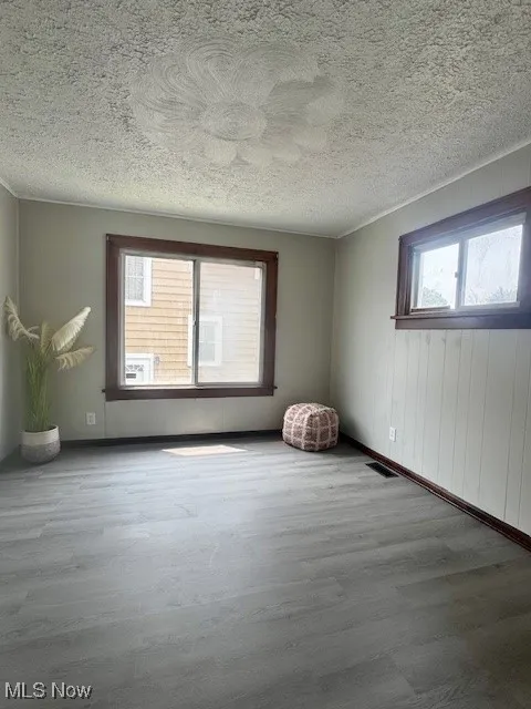 Unfurnished room with wood finished floors, a textured ceiling, and baseboards