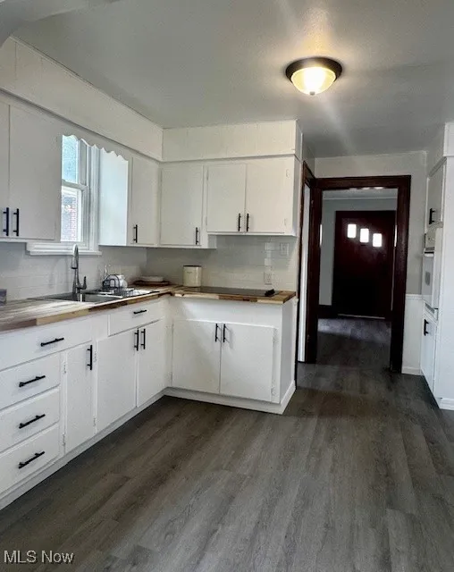 Kitchen featuring a sink, dark wood-style flooring, white oven, and white cabinets