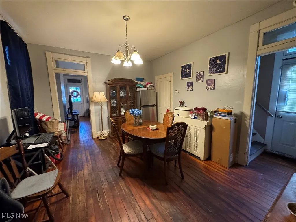 Dining area with dark wood-type flooring, stairway, and a chandelier