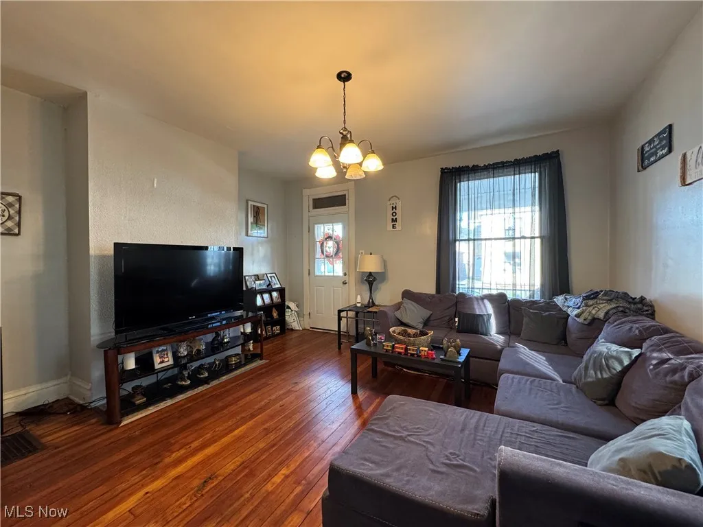 Living room featuring hardwood / wood-style floors, a chandelier, and a textured wall