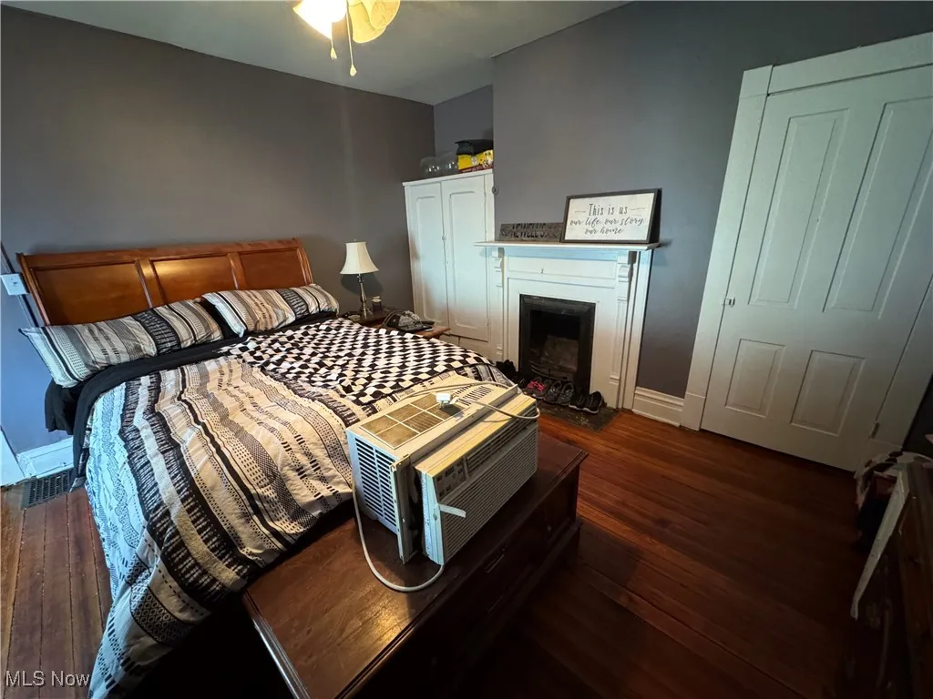 Bedroom with dark wood finished floors and a fireplace