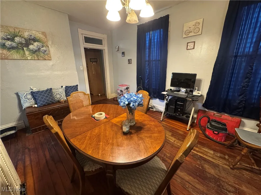 Dining area with hardwood / wood-style floors, a textured wall, and a chandelier