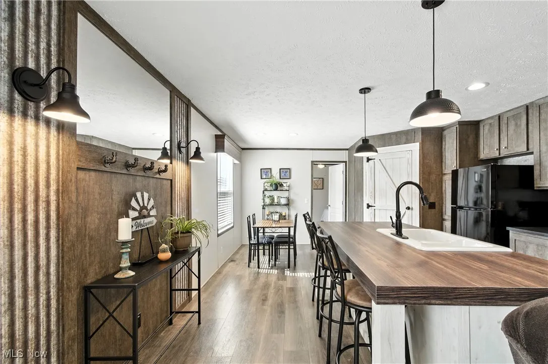 Kitchen with wooden counters, decorative light fixtures, dark wood-type flooring, a textured ceiling, and freestanding refrigerator