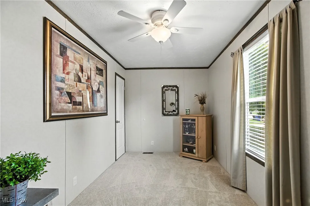 Home office featuring ornamental molding, light colored carpet, and ceiling fan