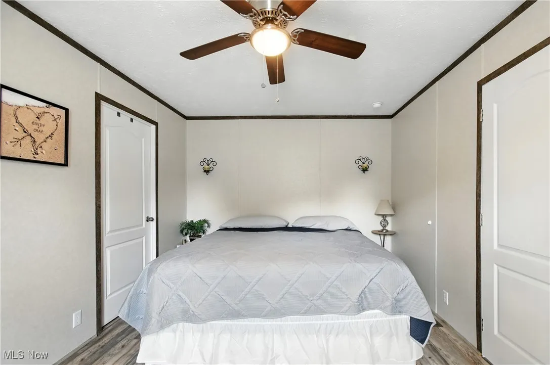 Bedroom with crown molding, wood finished floors, and ceiling fan