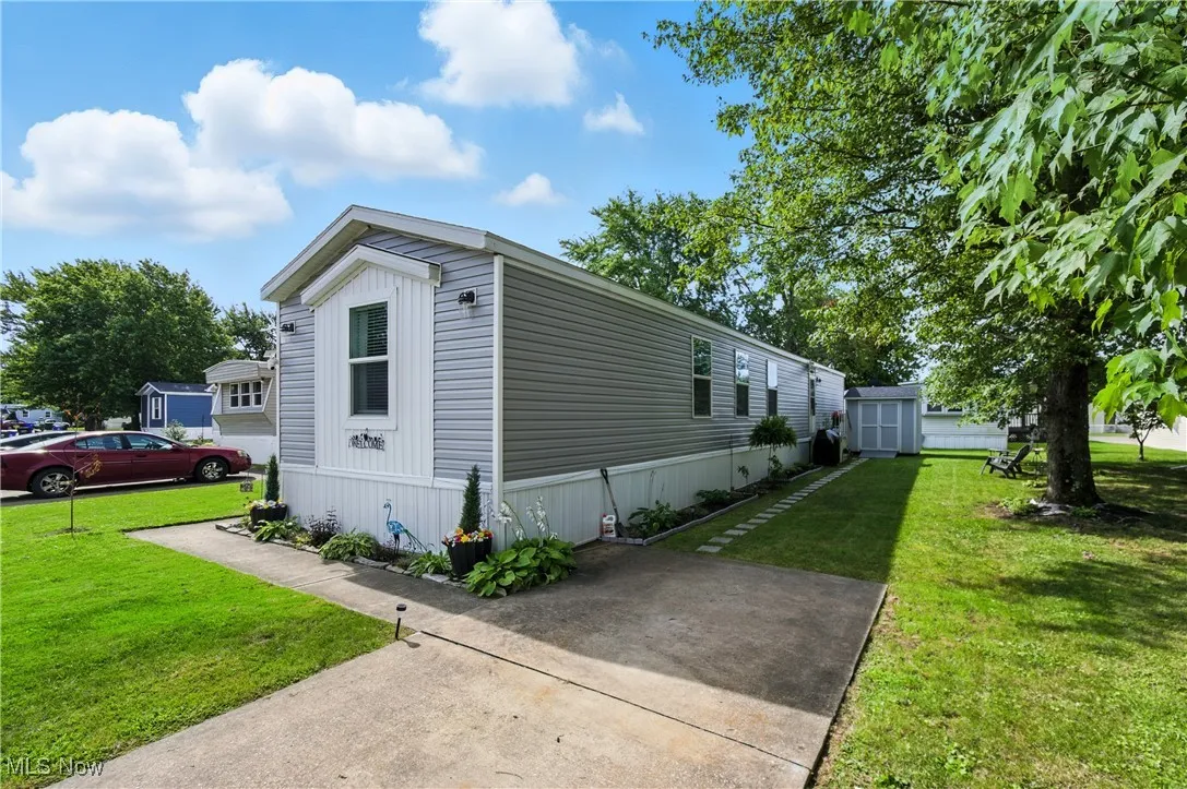 View of side of home with a lawn and a shed