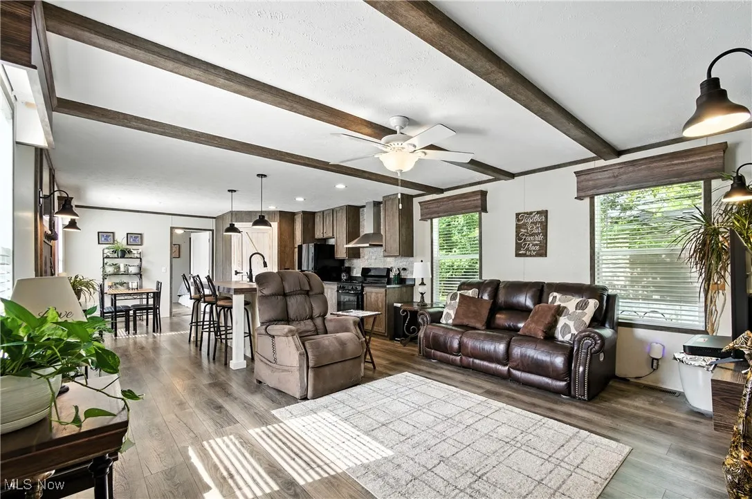Living area featuring beam ceiling, a ceiling fan, and dark wood finished floors