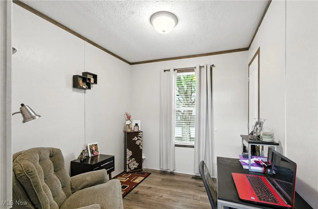 Office area with dark wood-type flooring, ornamental molding, and a textured ceiling