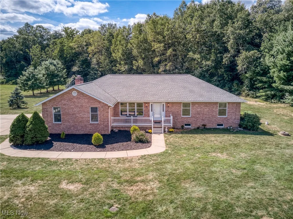 Ranch-style house with brick siding, covered porch, a front lawn, and a chimney