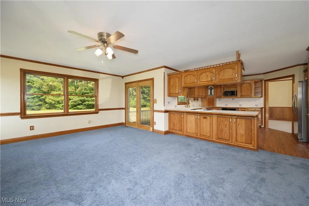 Kitchen featuring brown cabinets, open floor plan, light carpet, crown molding, and a peninsula