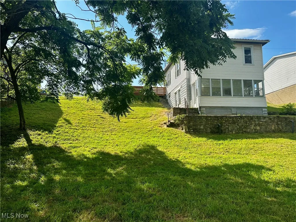 View of the grassy yard, showing the back of the house and sunroom.