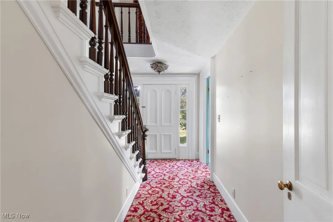 Carpeted entryway featuring a textured ceiling and stairway