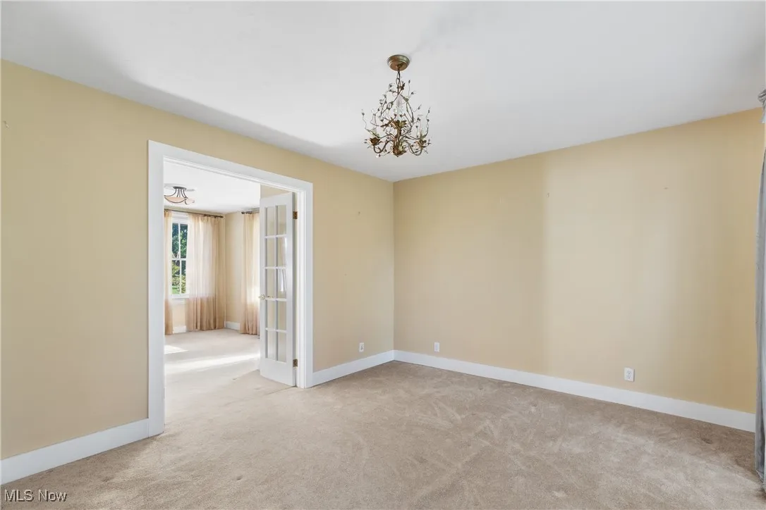 Unfurnished room with light colored carpet and a chandelier