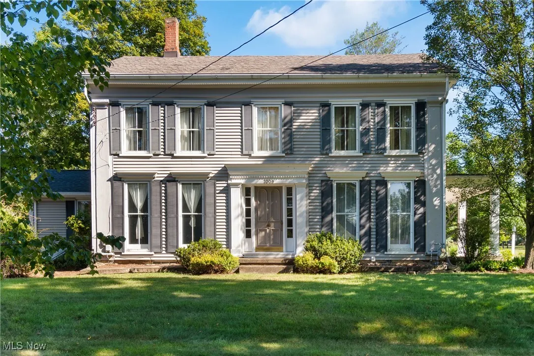 View of front of property with a chimney, a front lawn, and a shingled roof