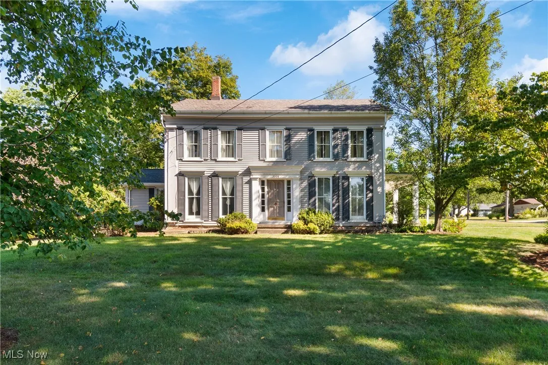 Colonial home featuring a chimney and a front yard