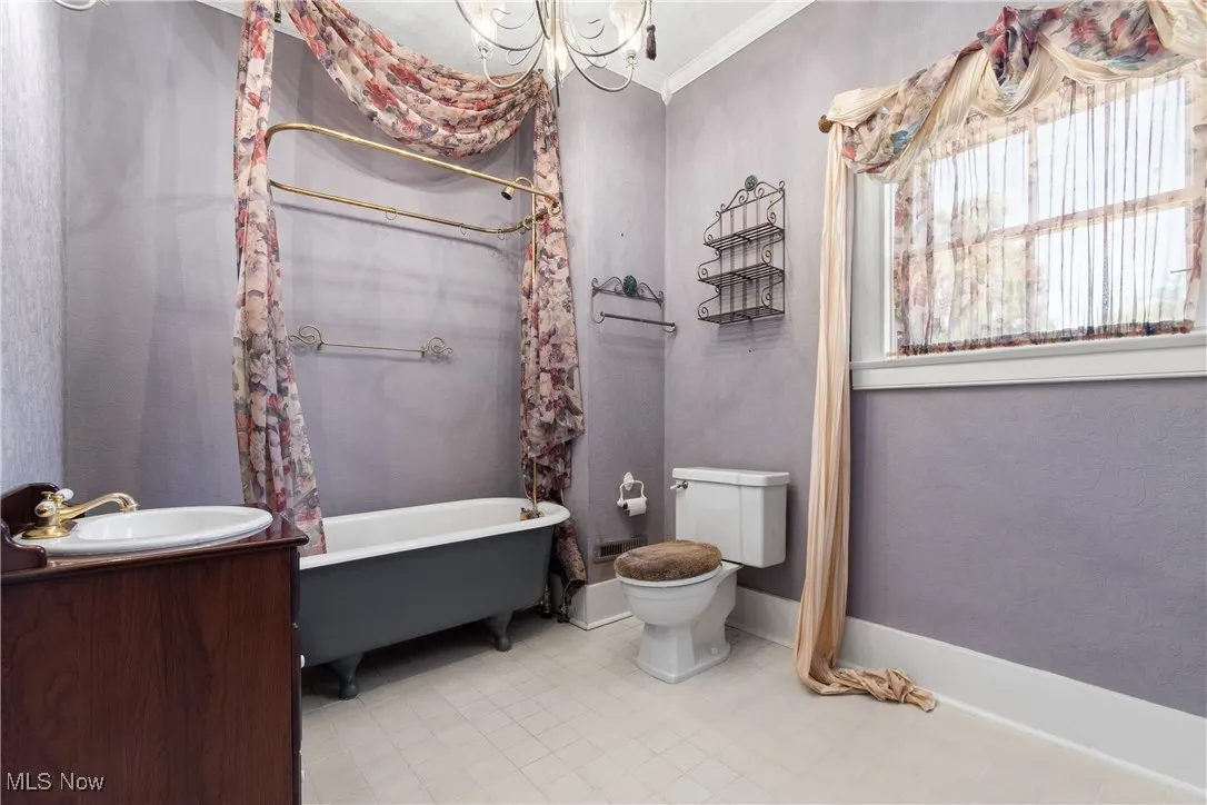 Full bath featuring crown molding, a chandelier, vanity, and a combined bath / shower with freestanding tub