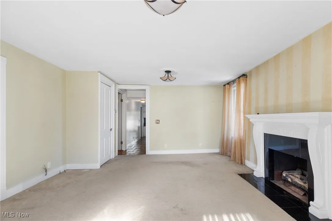 Unfurnished living room featuring carpet floors and a tiled fireplace