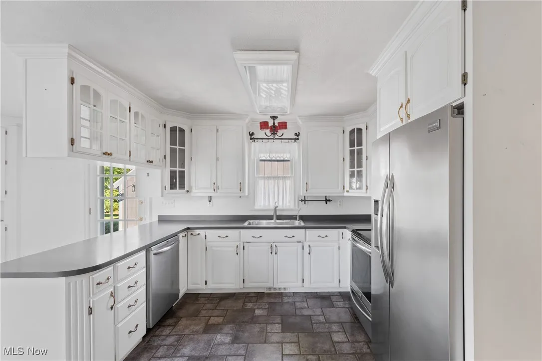 Kitchen featuring glass insert cabinets, white cabinets, and stone finish floors