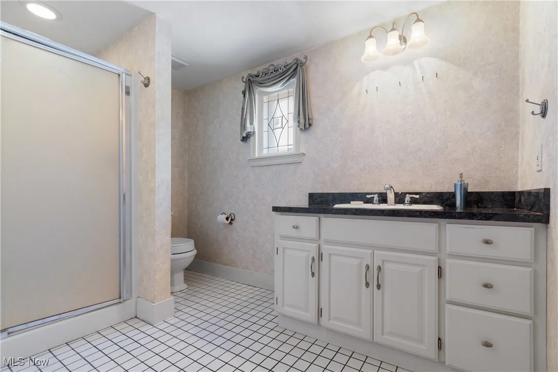 Full bath with light tile patterned floors, vanity, and a shower stall