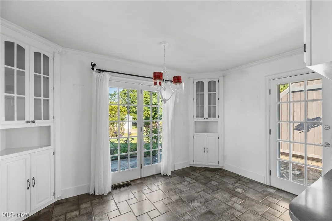 Unfurnished dining area with dark stone finish floors, a chandelier, ornamental molding, and built in shelves