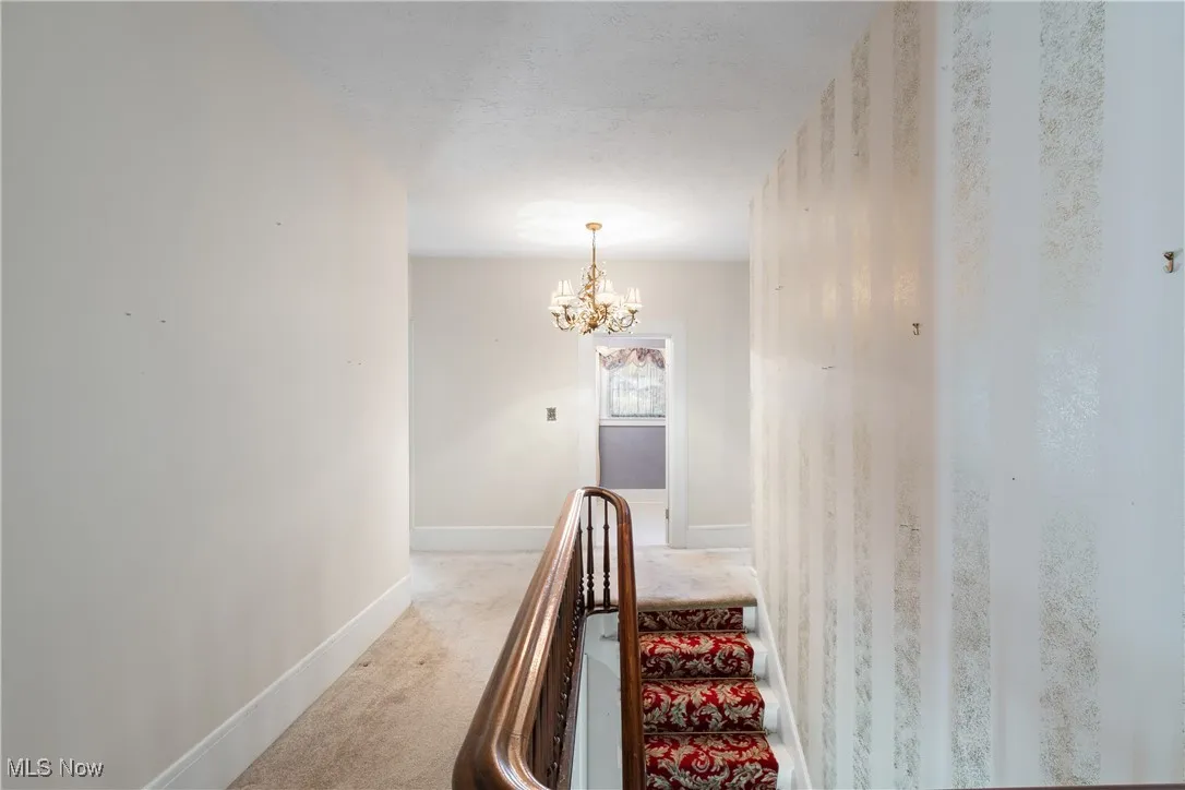 Staircase featuring a chandelier, carpet flooring, and a textured ceiling