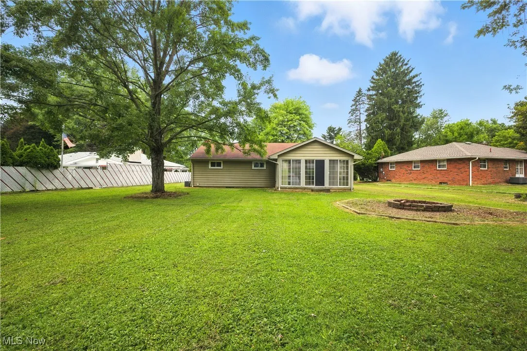 View of yard with an outdoor fire pit and a sunroom