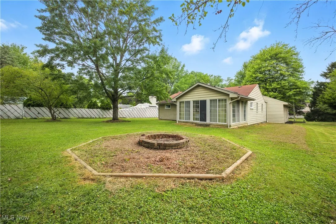 View of yard featuring a sunroom and an outdoor fire pit