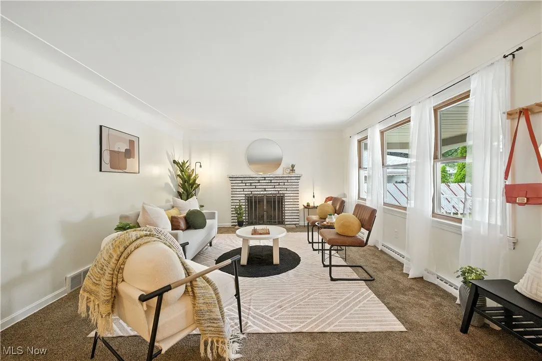 Carpeted living room featuring a brick fireplace and a baseboard heating unit