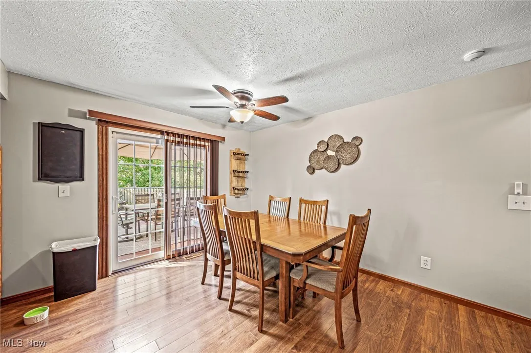 Dining space featuring light wood-type flooring, a textured ceiling, and a ceiling fan