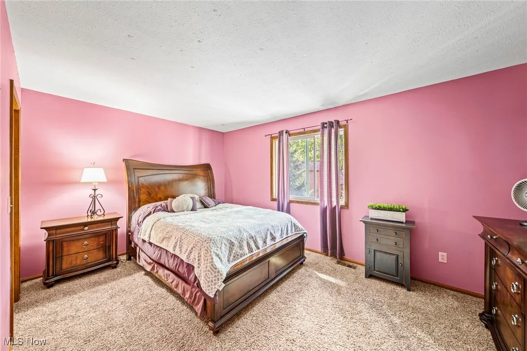 Bedroom with light carpet and a textured ceiling