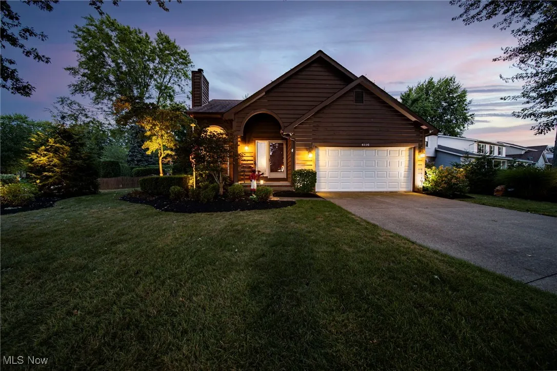 View of front of house with concrete driveway, a lawn, a chimney, and a garage