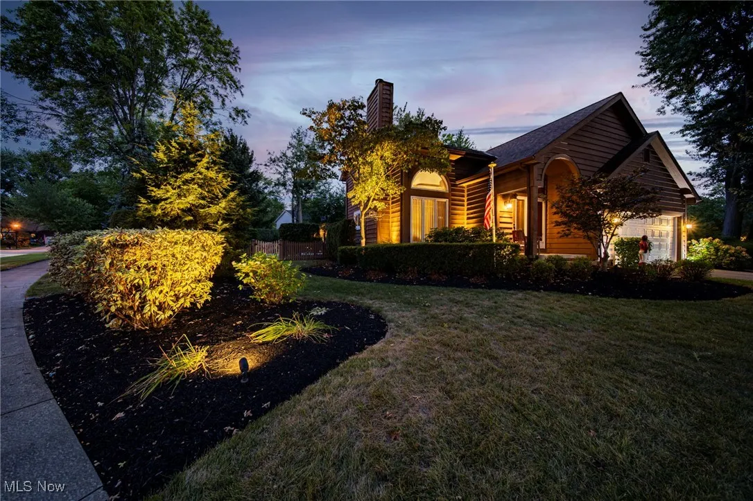 Property exterior at dusk with a garage, a yard, and a chimney